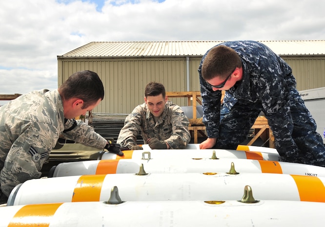 A U.S. Navy mineman, from Navy Munitions Command Unit Charleston, and U.S. Air Force technicians, from the 5th Munitions Squadron, rotate an inert MK-62 Quick Strike Mine to secure a MK-15 tail fin during a mine build at Royal Air Force Fairford, England, June 10, 2015. The mines were built for a BALTOPS 15 exercise where B-52H Stratofortresses tested their ability to precisely drop munitions into a target zone off the coast of Sweden. BALTOPS provides an opportunity for personnel from different services and nations to engage in realistic maritime training to build experience and teamwork and strengthen interoperability. (U.S. Air Force photo/Senior Airman Malia Jenkins)  