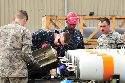 U.S. Navy minemen, from Navy Munitions Command Unit Charleston, and U.S. Air Force technicians, from the 5th Munitions Squadron, attach a MK-15 tail fin to an inert MK-62 Quick Strike Mine at Royal Air Force Fairford, England, June 10, 2015. The inert mine was loaded onto a B-52H Stratofortress forward deployed to RAF Fairford to participate in multi-national exercises, train with the United States’ allies and partners and showcase the aircraft’s capabilities. (U.S. Air Force photo/Senior Airman Malia Jenkins)  