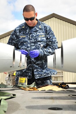 U.S. Navy Chief Petty Officer Alex Sanchez, Navy Munitions Command Unit Charleston mineman, greases a piece of equipment for an inert MK-62 Quick Strike Mine at Royal Air Force Fairford, England, June 10, 2015. The inert mine was loaded onto a B-52H Stratofortress participating in the BALTOPS 15 exercise. BALTOPS demonstrates America’s shared commitment with NATO allies and partners to promote peace and security in the region. (U.S. Air Force photo/Senior Airman Malia Jenkins)   