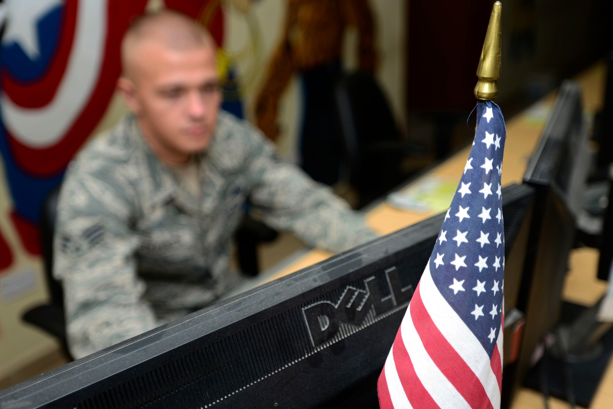 U.S. Air Force Senior Airman Vadim Poleanschi, a 386th Expeditionary Logistic Readiness Squadron logistic specialist, displays an American flag behind his computer monitor at an undisclosed location in Southwest Asia on June 3, 2015. Poleanschi applied to become a United States citizen in late 2013, after joining the AF. (U.S. Air Force photo by Senior Airman Racheal E. Watson/Released)