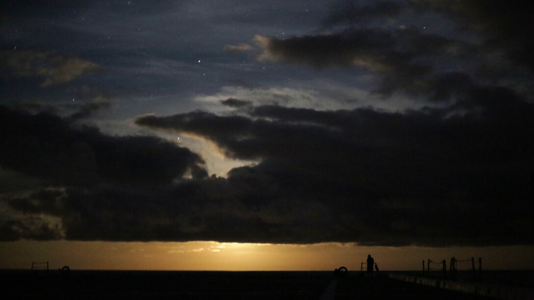 A sailor stands watch on the flight deck, in the middle of the night, as the moon reflects off the water as the USS San Antonio crosses the Atlantic Ocean on the way to BALTOPS 2015 May 31, 2015.  Approximately 5,600 ground, maritime and air forces from participating nations will demonstrate air defense, maritime interdiction, anti-subsurface warfare, and amphibious operations in a joint environment to ensure regional security.