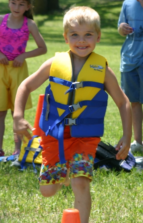 A child having fun running the life jacket relay race during a water safety event.
