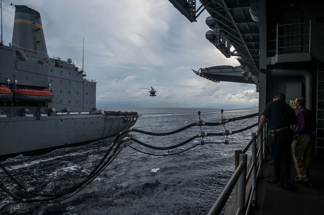 U.S. Marines and Sailors with the 15th Marine Expeditionary Unit and Essex Amphibious Ready Group watch an MH-60S Sea Hawk pick up supplies from the USNS Walter S. Diehl (T-AO 193) and transport them to the USS Essex (LHD 2) during a replenishment-at-sea in the South China Sea, June 14, 2015. Marines and Sailors helped unload mail and supplies to distribute throughout the ship as they transition to their 5th Fleet area of responsibility. (U.S. Marine Corps photo by Cpl. Anna Albrecht/Released)