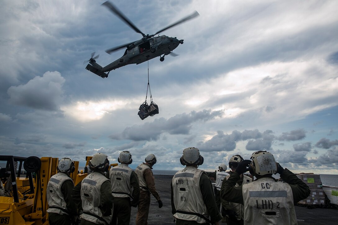 U.S. Marines with the 15th Marine Expeditionary Unit watch as an MH-60S Sea Hawk transports mail and supplies to the USS Essex (LHD 2) during a replenishment-at-sea in the South China Sea, June 14, 2015. These combat cargo Marines were responsible for moving the mail and supplies from the flight deck into the rest of the ship. The USS receives fuel and supplies at sea in order to continue its mission without stopping forward progress as they transition to their 5th Fleet area of responsibility. (U.S. Marine Corps photo by Cpl. Anna Albrecht/Released)