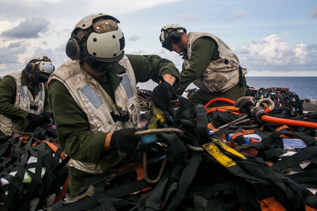 U.S. Marines with the 15th Marine Expeditionary Unit unwrap gear and supplies during a replenishment-at-sea aboard the USS Essex (LHD 2) in the South China Sea, June 14, 2015. These combat cargo Marines were responsible for getting the supplies from the flight deck into the rest of the ship. (U.S. Marine Corps photo by Cpl. Anna Albrecht/Released)