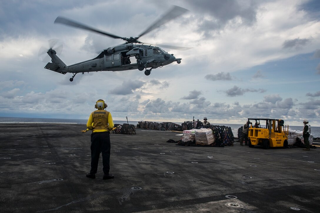 A U.S. Sailor with the Essex Amphibious Ready Group directs an MH-60S Sea Hawk during a replenishment-at-sea aboard the USS Essex (LHD 2) in the South China Sea, June 14, 2015. The USS Essex receives fuel and supplies at sea in order to continue its mission without stopping forward progress as they transition to their 5th Fleet area of responsibility. (U.S. Marine Corps photo by Cpl. Anna Albrecht/ Released)