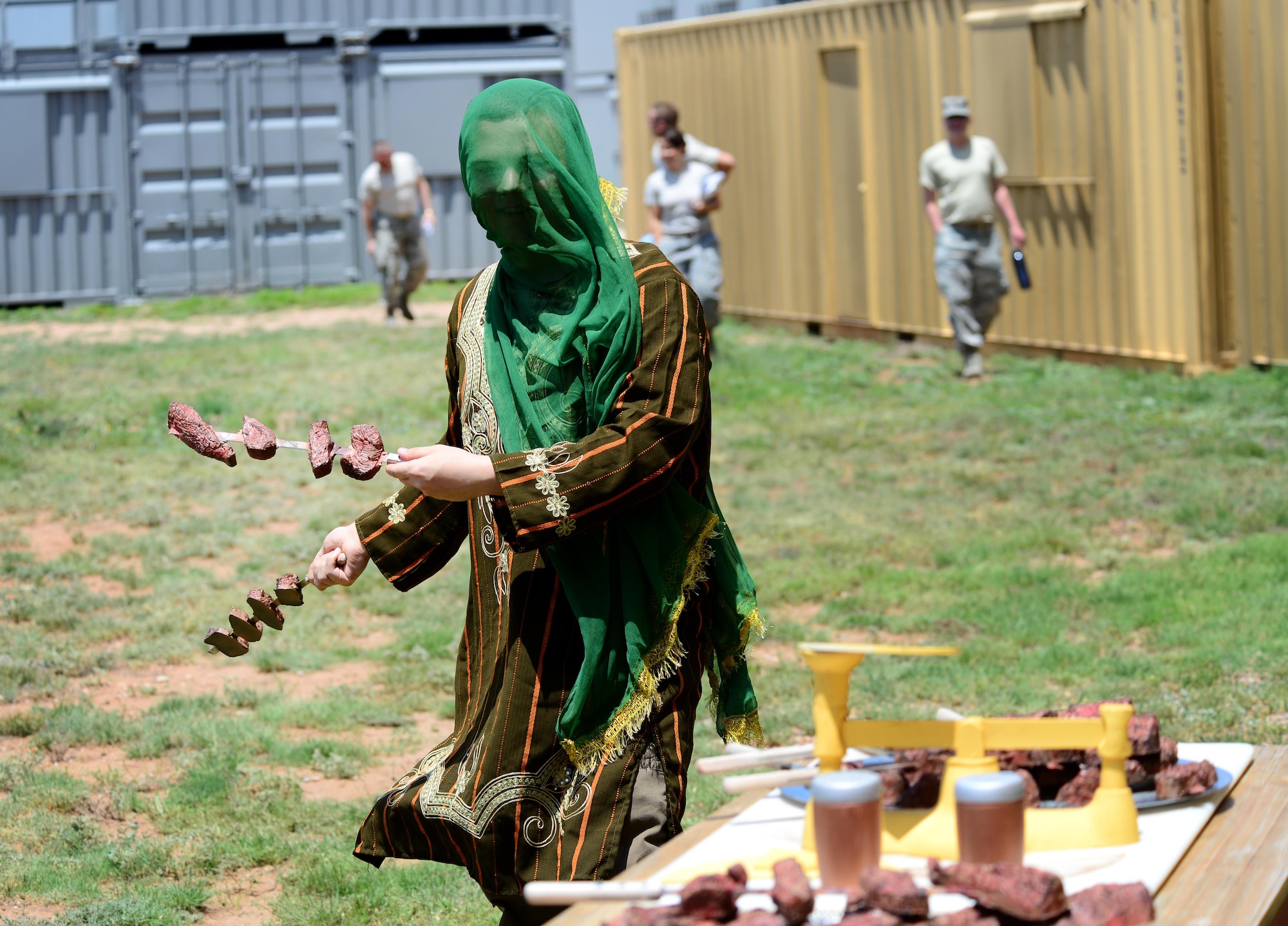 An opposing forces player offers kebabs to finance and contracting Air Commandos participating in an exercise June 9, 2015 at Melrose Air Force Range, N.M. During the exercise, finance and contracting Air Commandos received financial training and practiced managing contracts and contract personnel in a contingency environment. (U.S. Air Force photo/Airman 1st Class Shelby Kay-Fantozzi)