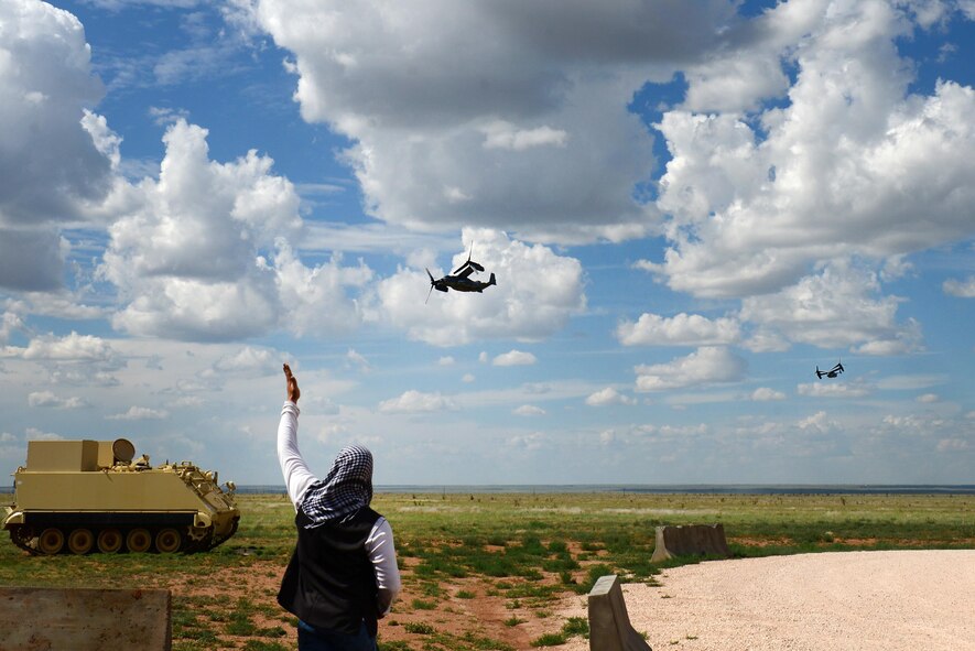 An opposing forces player waves to finance and contracting Air Commandos riding a CV-22 Osprey aircraft as part of an exercise June 9, 2015 at Melrose Air Force Range, N.M. During the exercise, finance and contracting Air Commandos received financial training and practiced managing contracts and contract personnel in a contingency environment. (U.S. Air Force photo/Airman 1st Class Shelby Kay-Fantozzi)