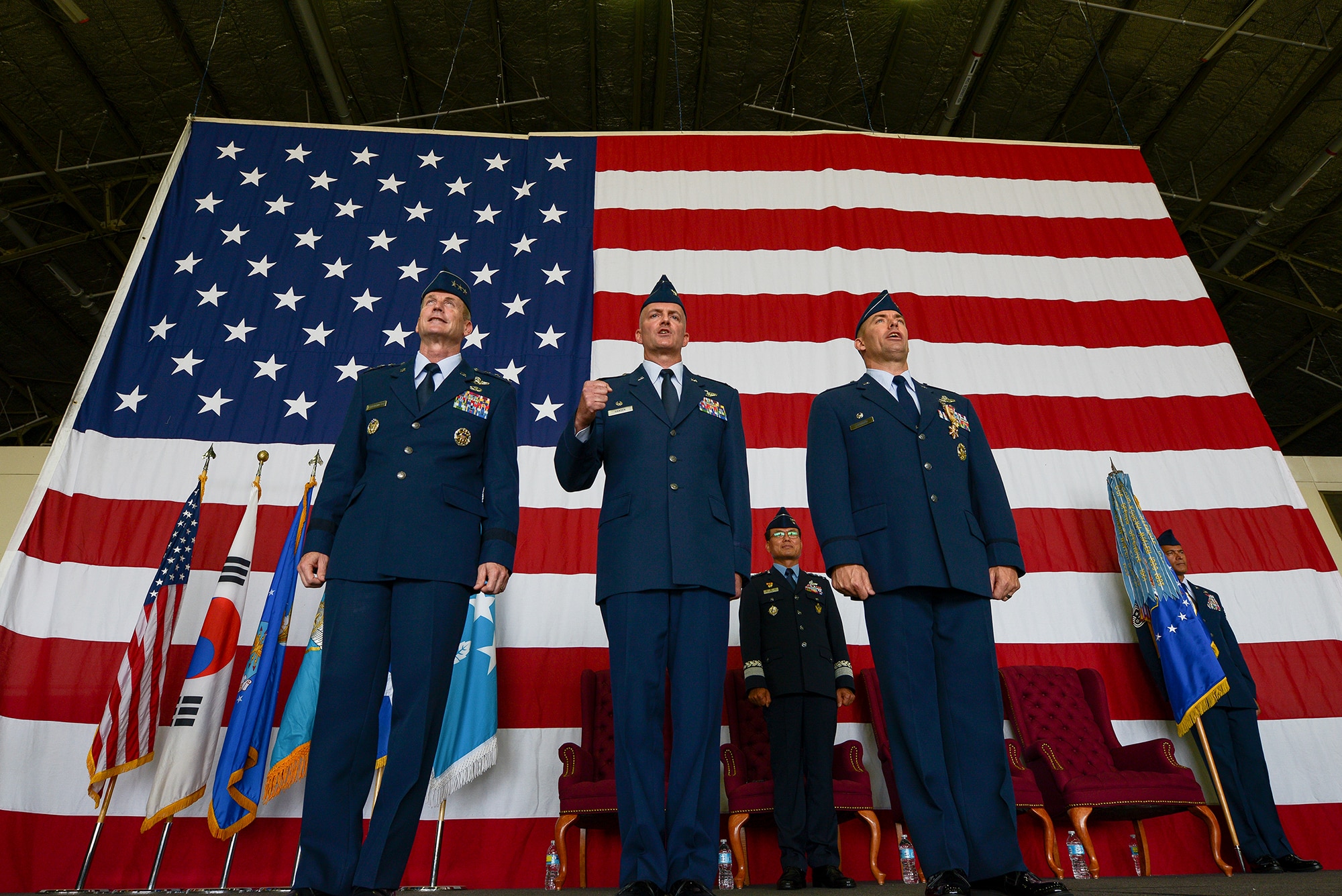 Lt. Gen. Terrence O'Shaughnessy, 7th Air Force commander, Col. Andrew Hansen, incoming 51st Fighter Wing commander, and Col. Brook Leonard, outgoing 51st Fighter Wing commander, sing the Air Force song at the end of the 51st FW change of command ceremony June 16, 2015, at Osan Air Base, Republic of Korea. The ceremony signified the passing of authority in the 51st FW. (U.S. Air Force photo by Staff Sgt. Jake Barreiro/Released)
