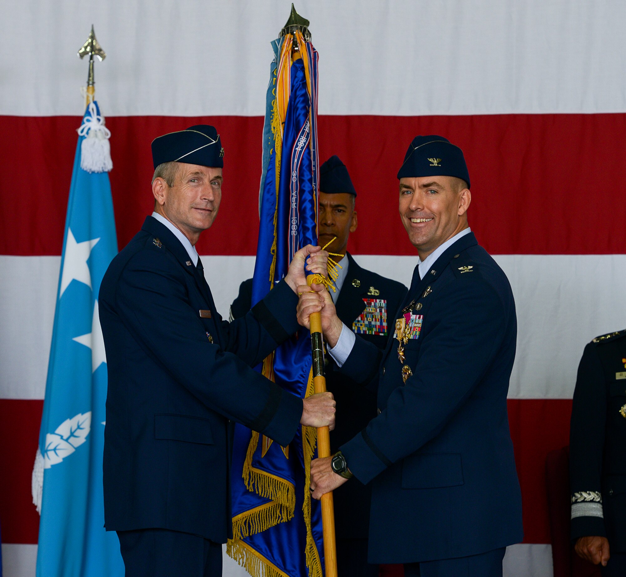 Col. Brook Leonard, outgoing 51st Fighter Wing commander, hands off the guideon to Lt. Gen. Terrence O'Shaughnessy, 7th Air Force commander, during the 51 FW change of command ceremony June 16, 2015, at Osan Air Base, Republic of Korea. Leonard began his command tour in July of 2013. (U.S. Air Force photo by Staff Sgt. Jake Barreiro/Released)