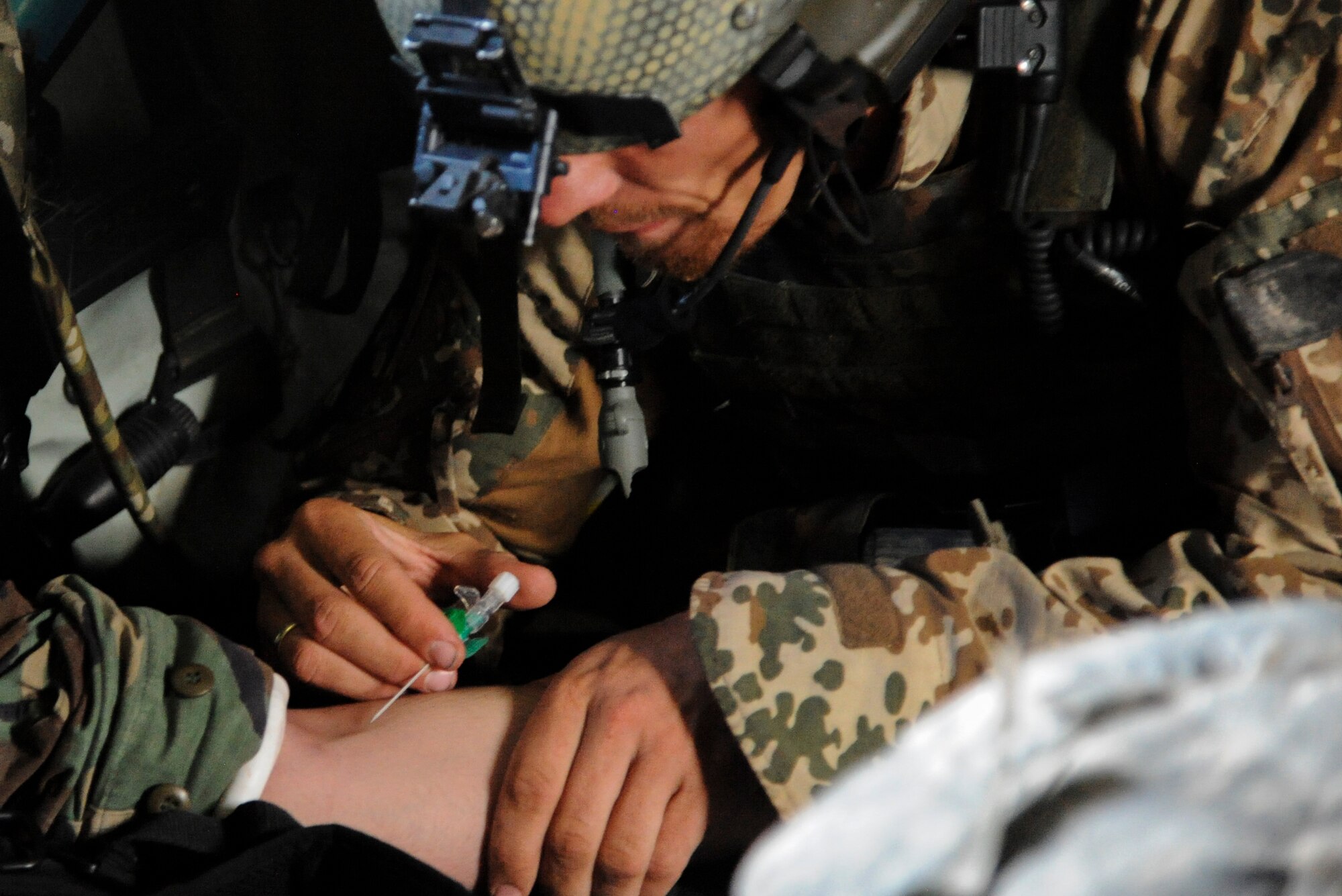 A German Air Force Helicopter Wing 64 pararescueman prepares to start an IV fluid resuscitation on a simulated casualty during an Angel Thunder 2015 mass casualty exercise at the Playas Research and Training Center, N.M., June 9, 2015. During this exercise, a security team patrolling a safe house hit an improvised explosive device so rescue personnel were called in to clear the town and locate survivors. (U.S. Air Force photo by Senior Airman Betty R. Chevalier/Released)