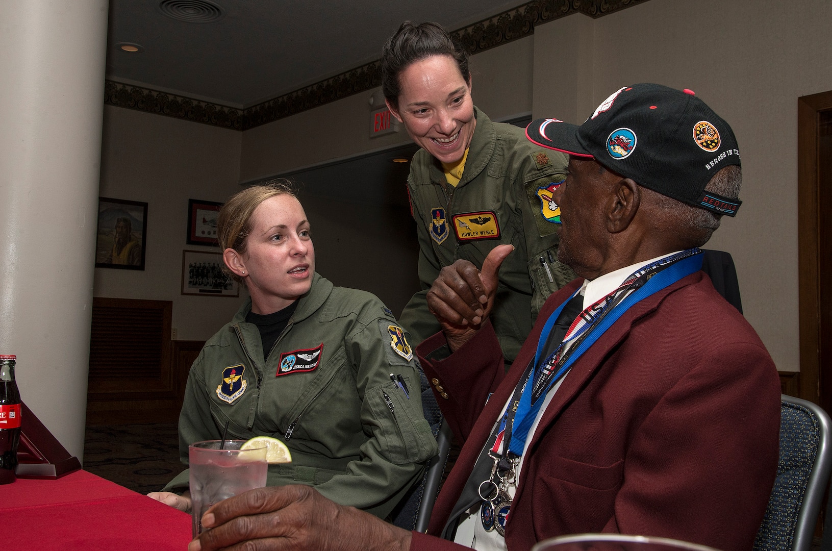 First Lieutenant Jessica Niswonger, 435th Flying Training Squadron, and Maj. Kristen Wehle, 451st Flying Training Squadron, visits with Mr. Theodore Johnson, documented original Tuskegee Airmen, during the Tuskegee Airmen Tribute, June 12, 2015, at Joint Base San Antonio-Randolph’s Parr Club.  Members of the JBSA-Randolph community celebrated the legacy of the first all-black unit by paying tribute to seven of the documented original Tuskegee Airmen members.  The Tuskegee Airmen distinguished themselves during World War II with more than 15,500 sorties and 1,500 missions in Europe and North Africa and earned numerous combat awards.  The event featured musical entertainment, comments by 12th Flying Training Wing leaders, an introduction of four Tuskegee Airmen present and a presentation of gifts to them. Members of the audience had an opportunity to mingle with the Tuskegee Airmen and listen to their stories. (U.S. Air Force photo by Johnny Saldivar/released)