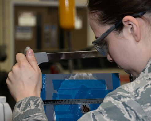 U.S. Air Force Airman 1st Class Maegen Correll, 100th Maintenance Squadron Aircraft Structural apprentice, works on a honeycomb core preparing the surface for fiberglass repair June 3, 2015, on RAF Mildenhall, England. The honeycomb core is used to distribute the load stress across the entirety of the panel. The Airman used the saw to cut the core straight and level with the surface of the panel. (U.S. Air Force photo by Gina Randall/Released)