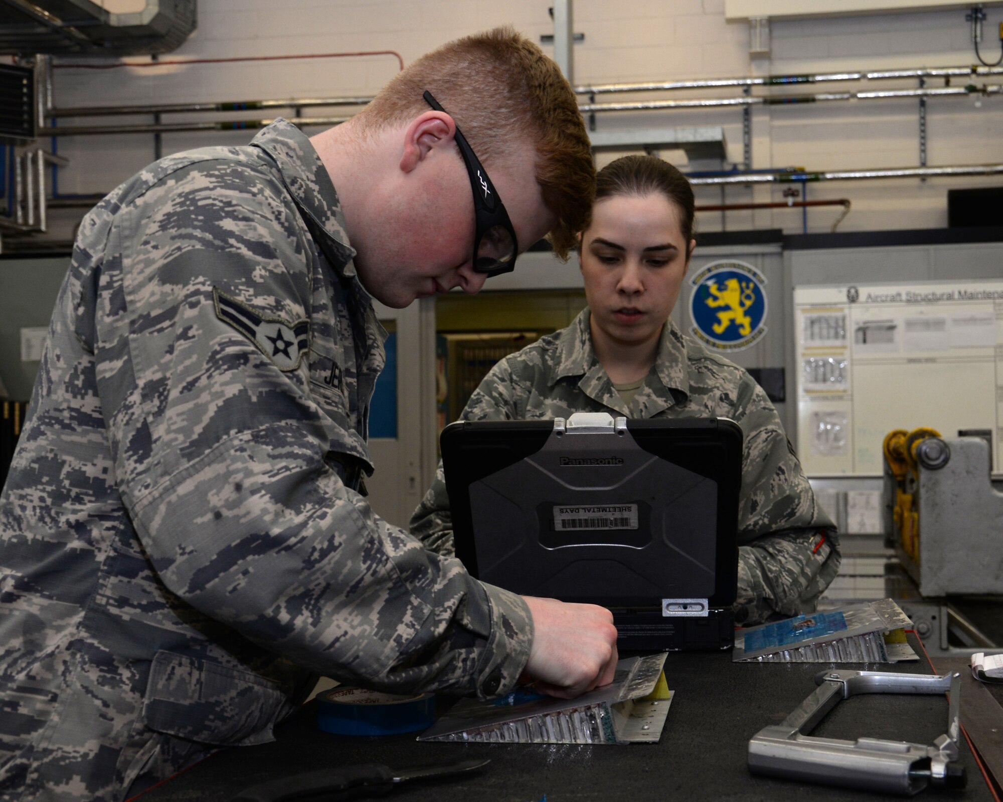 U.S. Air Force Airman 1st Class Donavan Jerles, left, 100th Maintenance Squadron Aircraft Structural apprentice from Gulf Shores, Ala., places tape on part of a flap while U.S. Air Force Airman 1st Class Maegen Correll, 100th MXS Aircraft Structural apprentice, checks technical orders June 3, 2015, on RAF Mildenhall, England. Flaps are devices used to alter the lift characteristics of a wing and are mounted on the trailing edges of the wings of a fixed-wing aircraft to reduce the speed at which the aircraft can be safely flown and to increase the angle of descent for landing. They shorten takeoff and landing distances. (U.S. Air Force photo by Gina Randall/Released)  