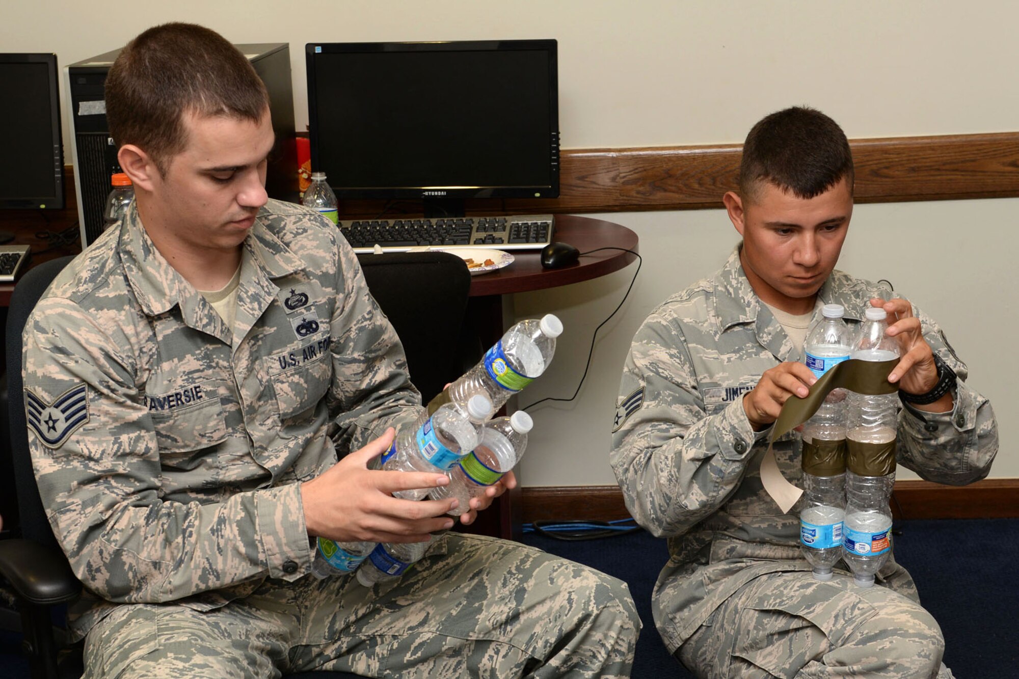 Staff Sgt. Zackery Traversie, 554th RED HORSE Squadron unit training manager, and Senior Airman Manuel Jimenez, 554th RHS engineering assistant, tape plastic bottles together to create a boat June 10, 2015, for the Boat Blitz at Andersen Air Force, Guam. One of the rules for the race was that boats can only consist of plastic bottles and tape; any other objects would have resulted in a disqualification. (U.S. Air Force photo by Airman 1st Class Joshua Smoot/Released)