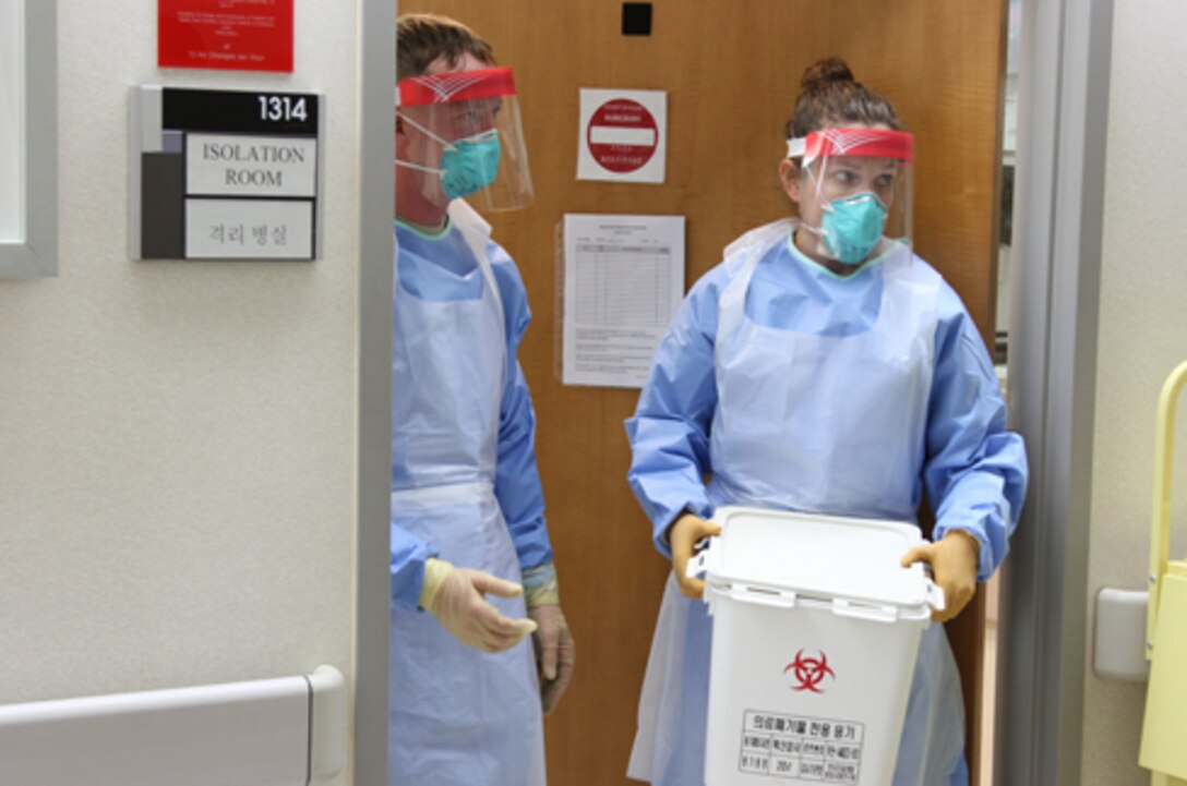 Capt. Kelsey Flagg, Brian Allgood Army Community Hospital emergency room charge nurse is assisted by Staff Sgt. Kyle Roberts, the senior ER medic, with removal of all contaminated waste products during the decontamination process. U.S. Forces Korea participated in the Highly Infectious Disease Full Scale Exercise, a Korean Center of Disease Control and Prevention-led exercise Mar. 31. The exercise provided ROK and US interagency and military participants training on responding to a simulated Ebola case. 