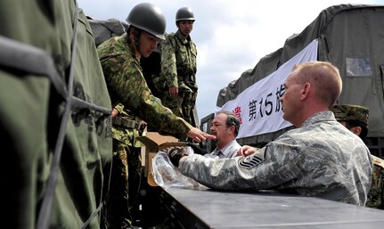 Air Force Master Sgt. Randall Dechant, deployment and distribution flight superintendant with the 18th Logistics Readiness Squadron, works with members of the 15 Brigade, Japan Ground Self Defense Force to load and prepare supplies on trucks headed to mainland Japan, March 16, 2011. Teams from the 15 Brigade, JGSDF are heading to northern Japan to aid earthquake and tsunami victims with trucks loaded with supplies including clothes, blankets and toiletries.