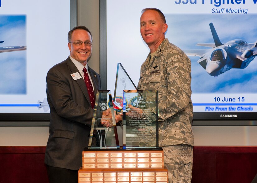 Eddie McAllister, Air Force Association Eglin Chapter 365 president, presents Col. Todd D. Canterbury, 33rd Fighter Wing commander, with the Jerry Waterman Award on Eglin Air Force Base, Florida, June 10, 2015. Established in 1967, the Jerry Waterman Award is presented to an active duty Air Force member who has made the most significant contribution to the Air Force for the past year. Col. Canterbury’s leadership over the 33 FW has led to program firsts that created successful methods of operations and training. The wing now has the ability to divert operations due to weather and evacuate in the event of a hurricane, perform night flights, aerial refueling and hot pit refueling in a training environment. Training opportunities have also doubled under his direction after removing F-35 Lightning II weather restrictions and the creation of a night-vision course. (U.S. Air Force photo/Staff Sgt. Marleah Robertson)