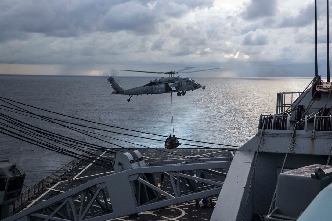 An MH-60S Sea Hawk with Essex Amphibious Ready Group deposits cargo on the flight deck of the USS Rushmore (LSD 47) during a replenishment at sea in the South China Sea, June 14, 2015. Marines and sailors with the 15th Marine Expeditionary Unit, and Essex ARG worked together to offload food, maintenance parts, and letters from home. (U.S. Marine Corps photo by Sgt. Emmanuel Ramos/Released)