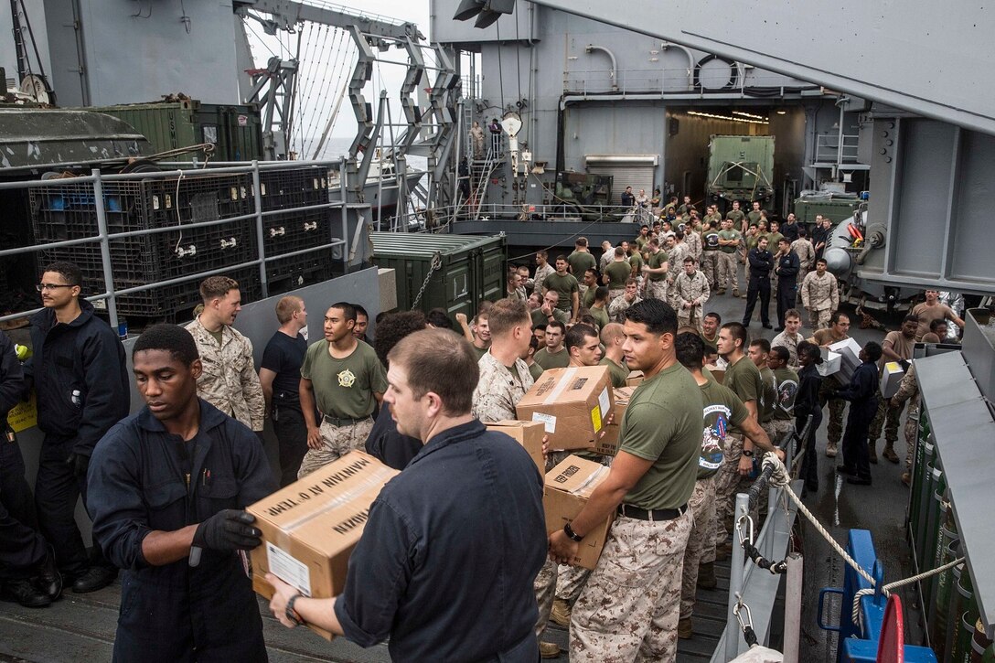 U.S. Marines and Sailors with the 15th Marine Expeditionary Unit and the Essex Amphibious Ready Group assist with offloading packages aboard the USS Rushmore (LSD 47) during a replenishment at sea in the South China Sea, June 14, 2015. Marines and sailors with the 15th MEU and Essex ARG worked together to off load food, maintenance parts, and letters from home. (U.S. Marine Corps photo by Sgt. Emmanuel Ramos/Released)