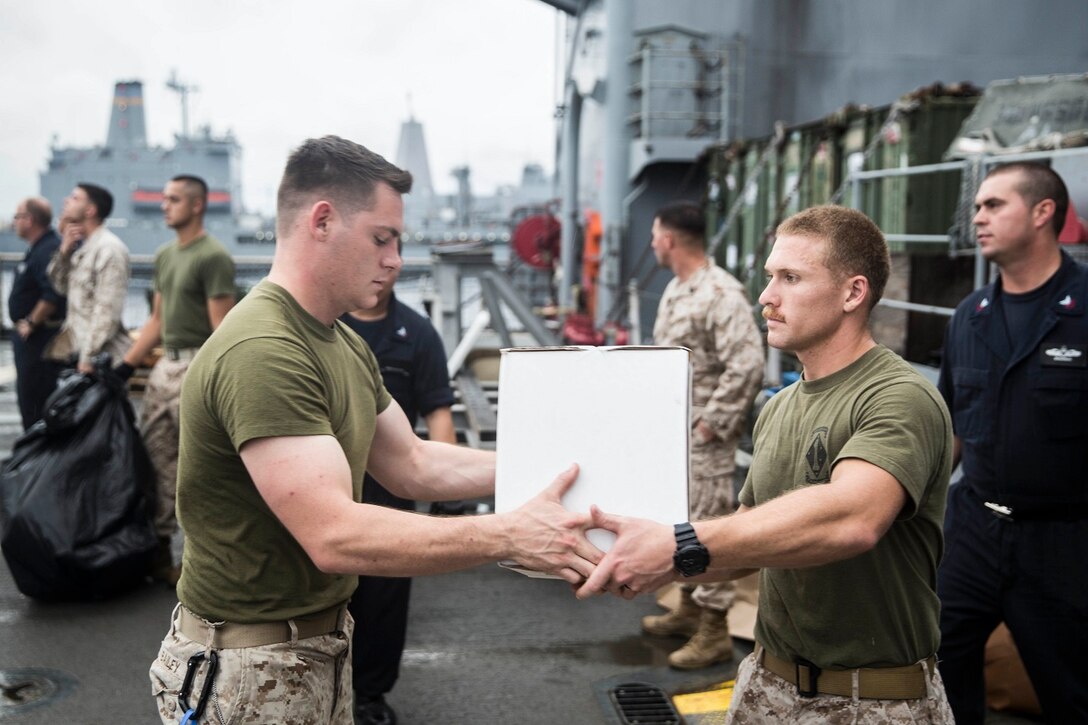 U.S. Marines and Sailors with the 15th Marine Expeditionary Unit and the Essex Amphibious Ready Group assist with offloading packages aboard the USS Rushmore (LSD 47) during a replenishment at sea in the South China Sea, June 14, 2015. Marines and sailors with the 15th MEU and Essex ARG worked together to offload food, maintenance parts, and letters from home. (U.S. Marine Corps photo by Sgt. Emmanuel Ramos/Released)