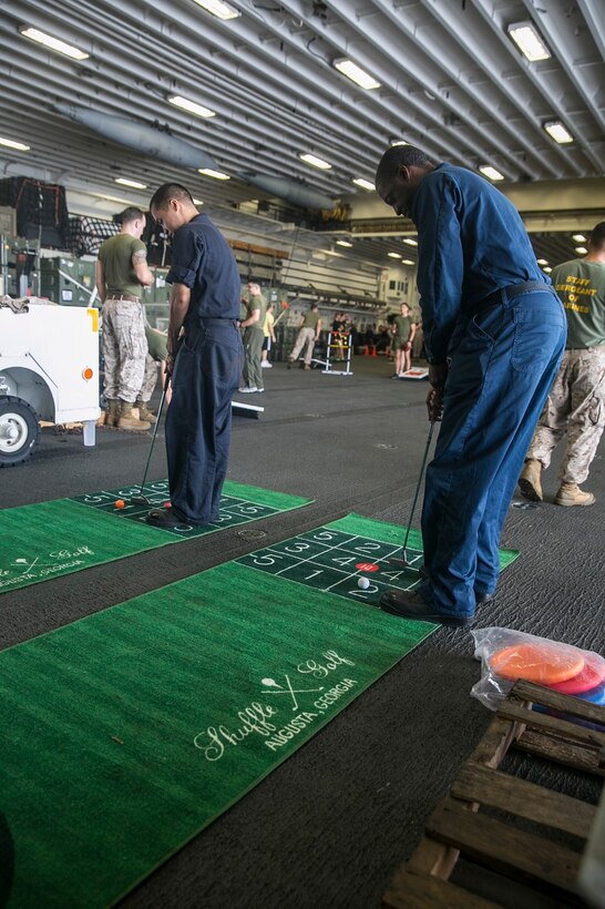 U.S. Sailors with the Essex Amphibious Ready Group play mini golf in the hangar bay of the USS Essex (LHD 2) at sea in the Strait of Malacca, June 15, 2015. The Marines with the 15th Marine Expeditionary Unit and Sailors with the Essex ARG enjoyed a “Steel Beach,” which consisted of grilling, music, and games. (U.S. Marine Corps photo by Cpl. Anna Albrecht/Released)