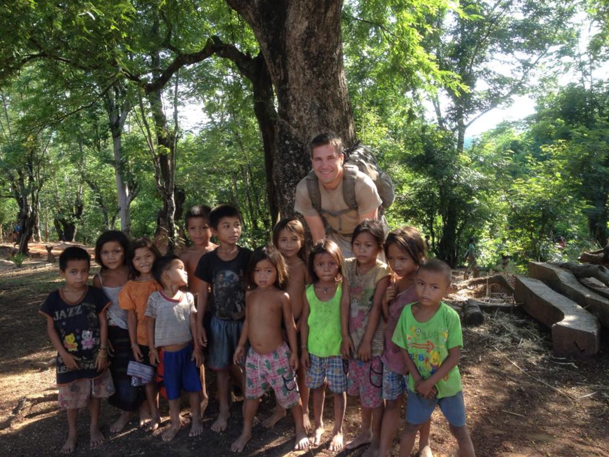Senior Master Sgt. Eric Eberhard, 419th Explosive Ordnance Disposal, poses with local children in Laos June 11. Eberhard is part of a recovery team tasked to excavate a Laos crash site from the Vietnam era. (Courtesy photo) 
