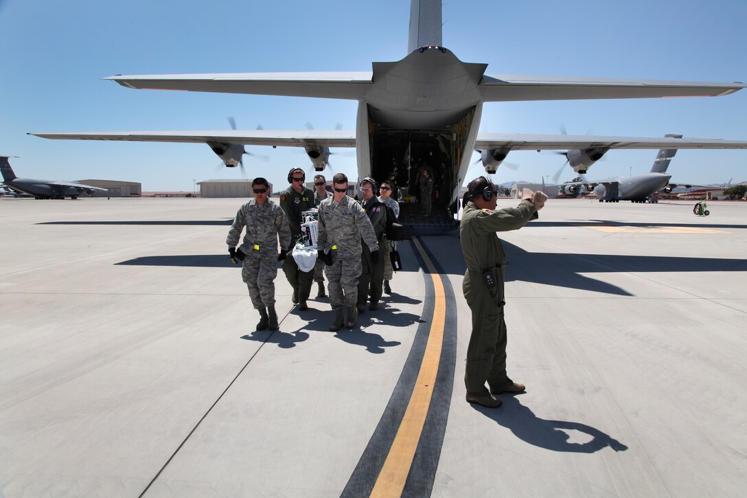 Critical care air transport teams and aeromedical evacuation crewmembers practice transporting critically ill patients on a C-130J Super Hercules from the California Air National Guard's 146th Airlift Wing, Channel Islands Air National Guard Station, California. during 349th Air Mobility Wing Air Force Specialty Code training June 6, 2015, at Travis Air Force Base, California.  In preparation for the training, the 349th Aeromedical Evacuation Squadron transformed the four-engine tactical transport into a flying hospital. In turn, the CCATT teams from the 60th Surgical Operations Squadron and the 349th Aeromedical Staging Squadron established onboard what was essentially a portable intensive care unit dedicated to one very ill, simulated, "patient."  (U.S. Air Force photo/Lt. Col. Robert Couse-Baker/Released)
