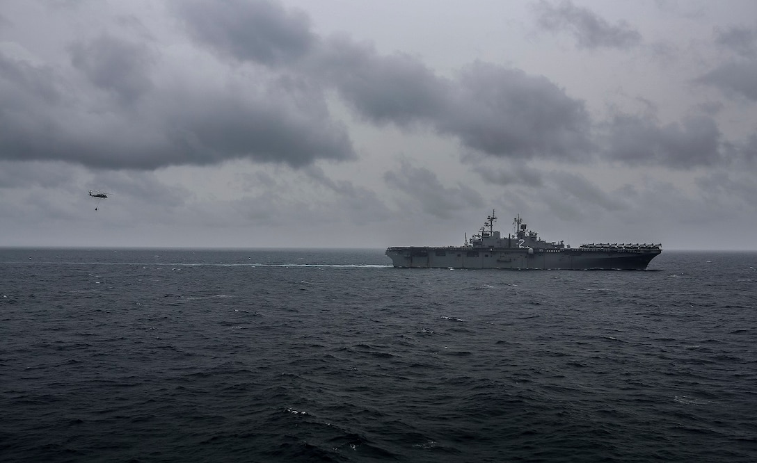 An MH-60S Seahawk conducts a vertical replenishment at sea with the USS Essex (LHD 2) in the South China Sea, June 14, 2015. The USS Essex receives fuel and stores at sea in order to continue its mission without stopping forward progress as they transition to their 5th Fleet area of responsibility. (U.S. Marine Corps photo by Sgt. Steve H. Lopez/Released)