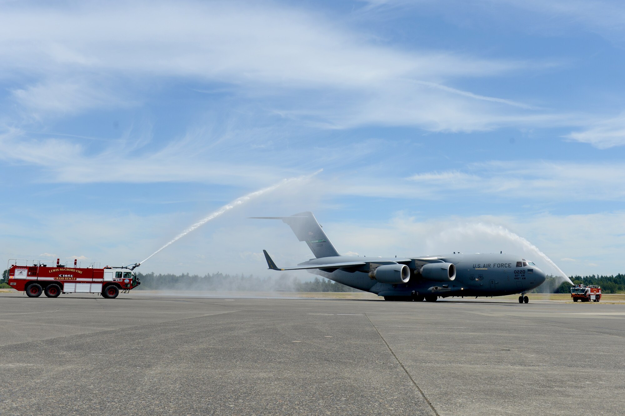 A C-17 Globemaster III taxis through an arc created by the showers from two firetrucks June 15, 2015, at Joint Base Lewis-McChord. Col. David Kumashiro, 62nd Airlift Wing commander, was greeted by his family and friends after parking the C-17. (U.S. Air Force photo/Airman 1st Class Keoni Chavarria)