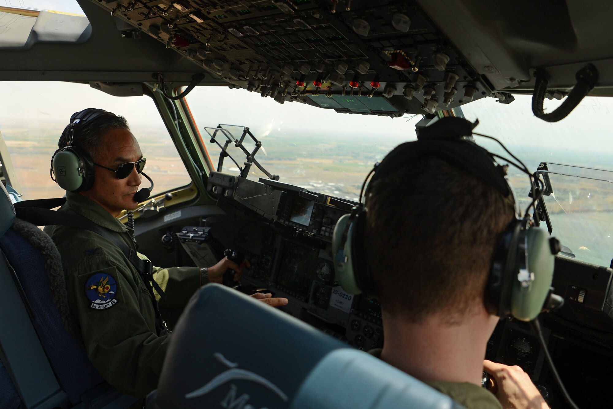 Col. David Kumashiro (left), 62nd Airlift Wing commander, talks to his co-pilot June 15, 2015, over central Washington state. Kumashiro’s final flight, also known as the “fini flight,” symbolized the end of his command as the wing commander. (U.S. Air Force photo by Staff Sgt. Tim Chacon)