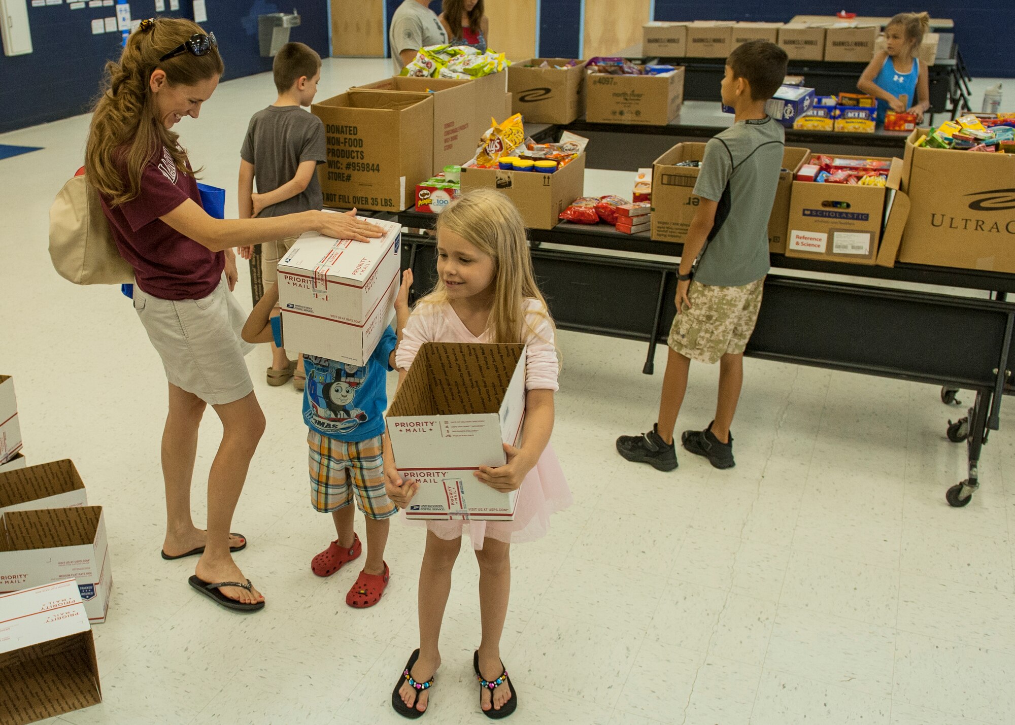 The Ebert family fills two boxes during the Company Grade Officer Council’s troop care drive at the Eglin Elementary School cafeteria June 5 at Eglin Air Force Base, Fla. The CGOC collected cards, letters, drawings and donations from 13 Okaloosa county schools. The boxes were filled with these items along with books, coffee, magazines, snacks and various comfort items for Eglin’s deployed Airmen. Some of the items were donated by the local community through the Airman and Family Readiness Center. Volunteers packed and mailed approximately 60 care packages for Eglin’s deployed. (U.S. Air Force photo/Ilka Cole)