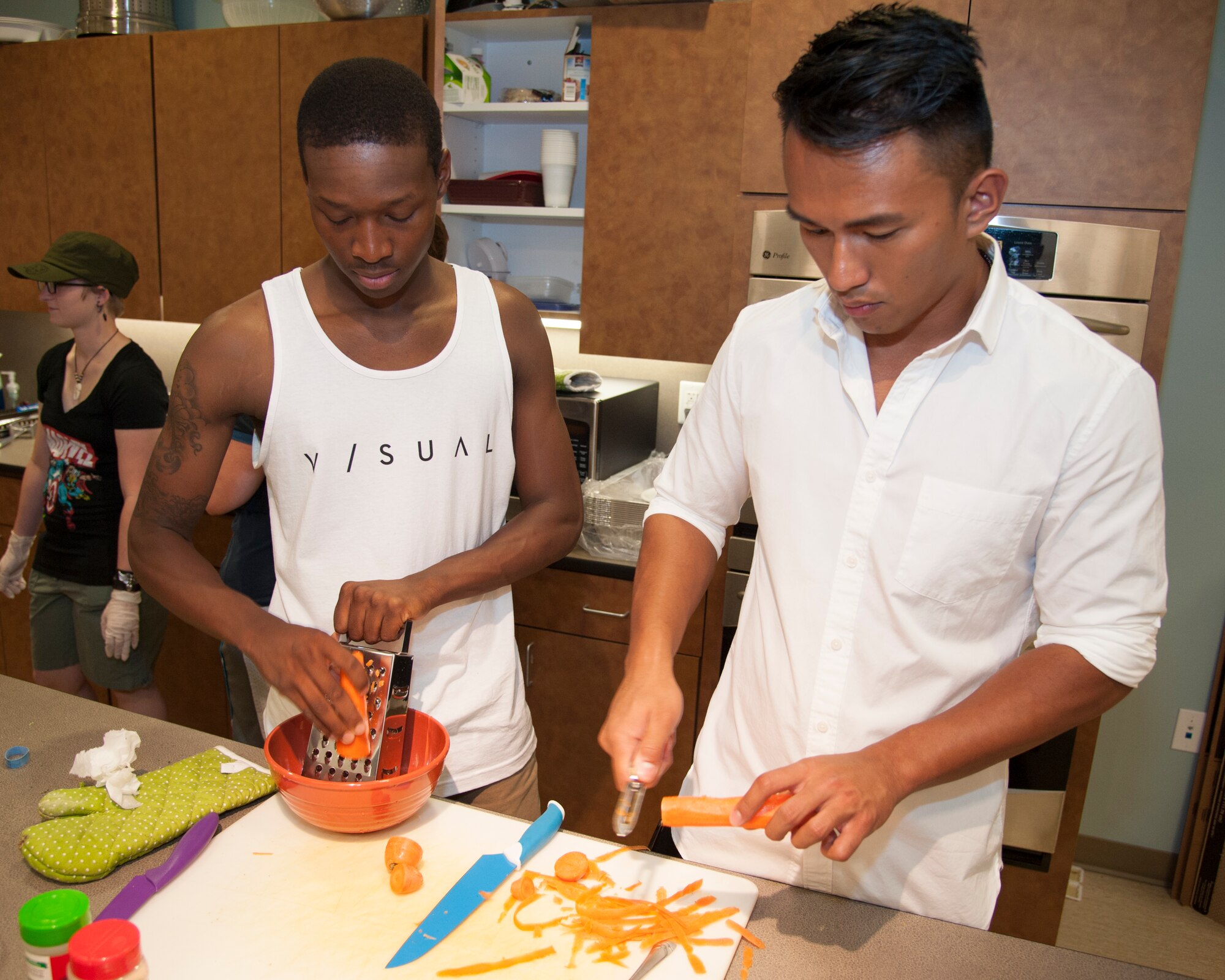 Airman 1st Class Dailan Gudger, 436th Security Forces Squadron patrolman, left, and Senior Airman Poler Oliveros, 436th Operations Support Squadron aircrew flight equipment technician, right, prepare carrots for a chicken Caesar salad June 9, 2015, at the Health Promotion Flight kitchen in the Fitness Center on Dover Air Force Base, Del. The purpose of the course is to teach Airmen, who live in the dorms, how to cook healthy meals. (U.S. Air Force photo/Senior Airman Jared Duhon) 