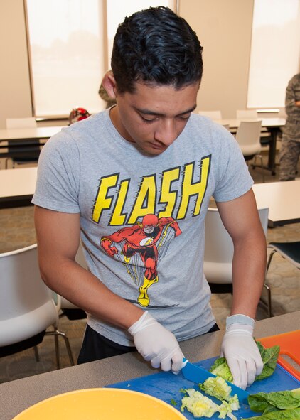 Airman 1st Class George Amezquita, 436th Aerial Port Squadron, cuts lettuce during a Dorm to Gourm class at the Health Promotion Flight kitchen in the Fitness Center on Dover Air Force Base, Del. The lettuce was used for the chicken Caesar salad which was one of three dishes prepared. (U.S. Air Force photo/Senior Airman Jared Duhon) 