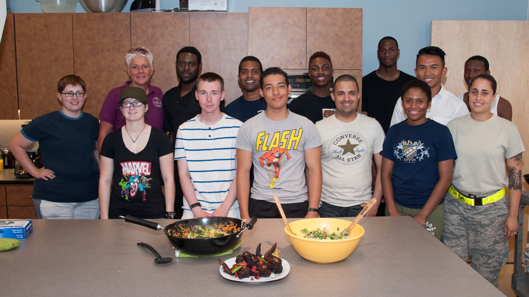 Team Dover Airmen and Dawne Nickerson-Banez, Mission Support Group’s 2015 honorary commander and founder of the Dorm to Gourm program, stand behind three chicken dishes they made June 9, 2015, at the Health Promotion Flight kitchen in the Fitness Center on Dover Air Force Base, Del. The prepared dishes were French bone-in jerk chicken, chicken Caesar salad, and a bacon-wrapped drumstick. (U.S. Air Force photo/Senior Airman Jared Duhon)  