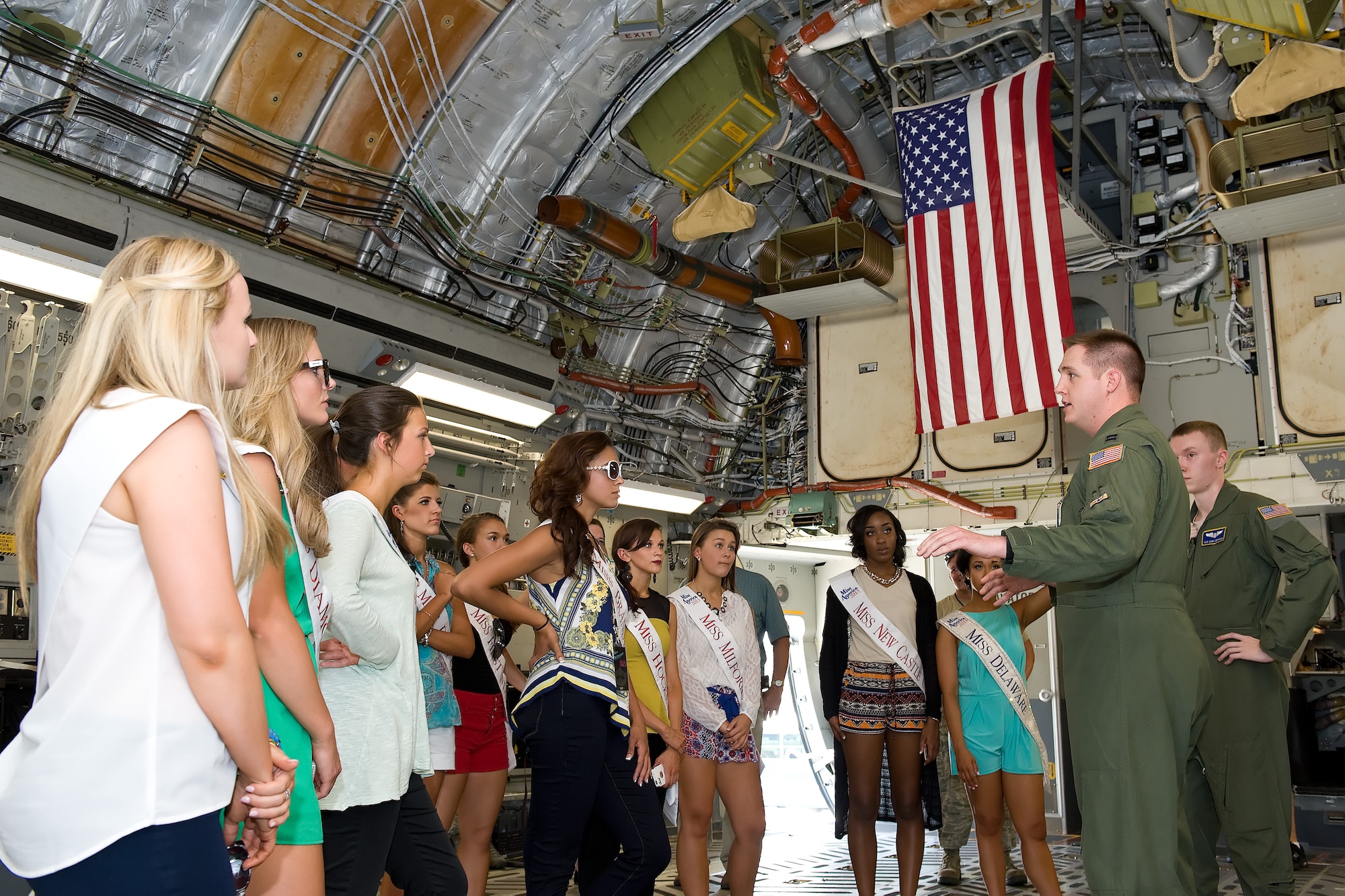 Capt. Hank Goldsmith, pilot, and Airman 1st Class Cody Deranick, loadmaster, both assigned to the 3d Airlift Squadron, brief Miss Delaware 2015 contestants on the operational capabilities of the C-17A Globemaster III June 11, 2015, on Dover Air Force Base, Del. Contestants, as well as the reigning Miss Delaware, Brittany Lewis, met with the C-17 aircrew and aircraft maintainers while visitint visiting the base. (U.S. Air Force photo/Roland Balik)