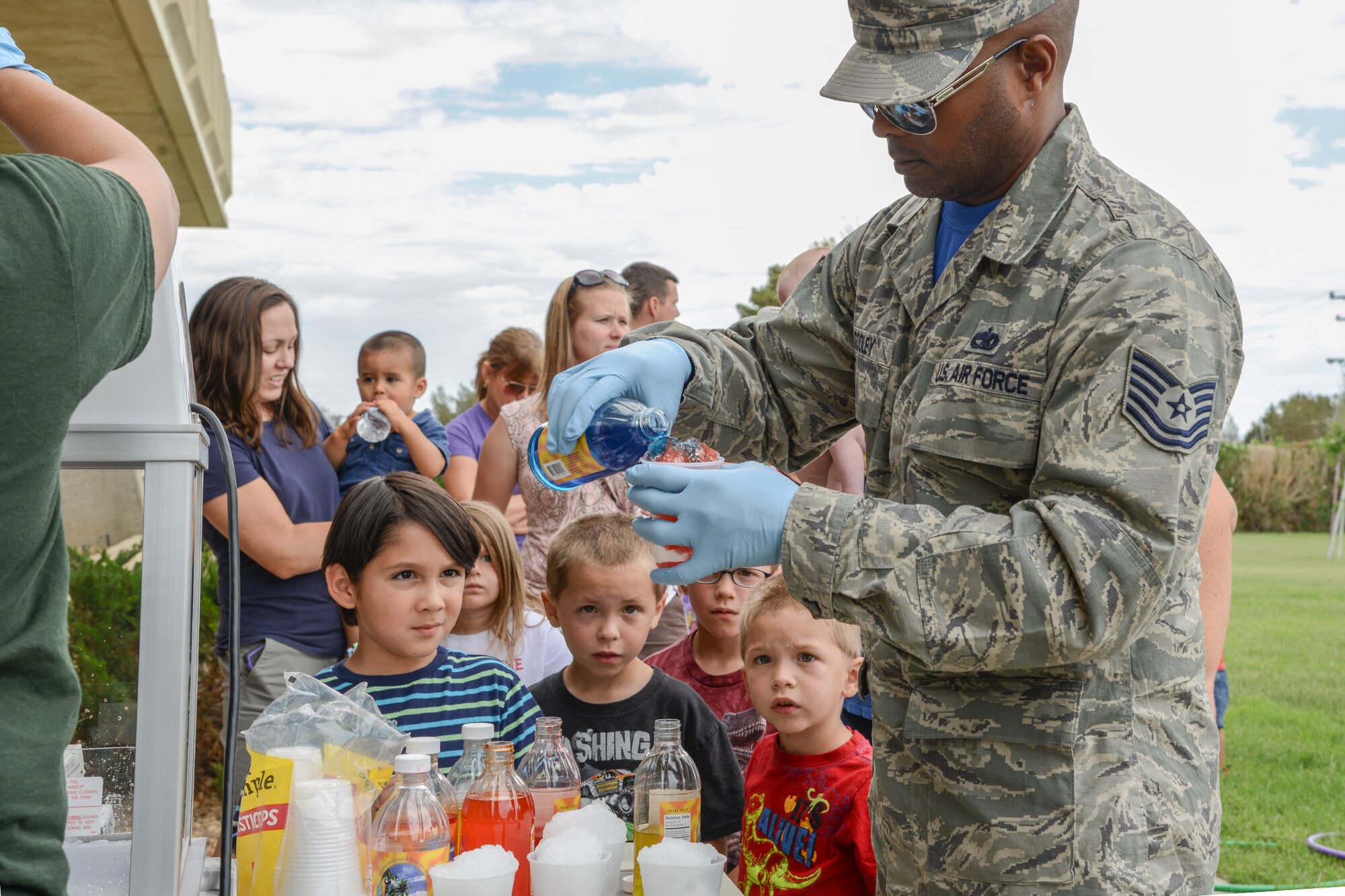 Volunteers from the 412th Operations Support Squadron and the 31st Test and Evaluation Squadron help set up, tear down and run the summer reading event June 12. For a sweeter summer treat, Tech. Sgt. Jonathan Cooley, 31st TES, prepares snow cones while the children wait patiently. (U.S. Air Force photo by Rebecca Amber)