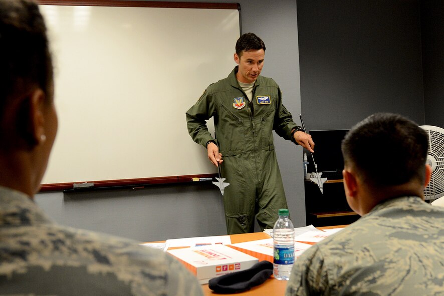 U.S. Air Force Capt. James Byrd, 55th Fighter Squadron D-Flight commander, F-16 instructor pilot, demonstrates different maneuvers the F-16CM Fighting Falcon pilots use during the Operations Immersion Program at Shaw Air Force Base, S.C., June 9, 2015. During the program, Airmen sat through the different briefs pilots undertake for their mission, as well as received a tour of the weapons load barn where 55th FS personnel described the different munitions they use as well as different aspects the F-16 is capable of, and then the Airmen were able to attempt to fly in a flight simulator. (U.S. Air Force photo by Senior Airman Diana M. Cossaboom/Released)