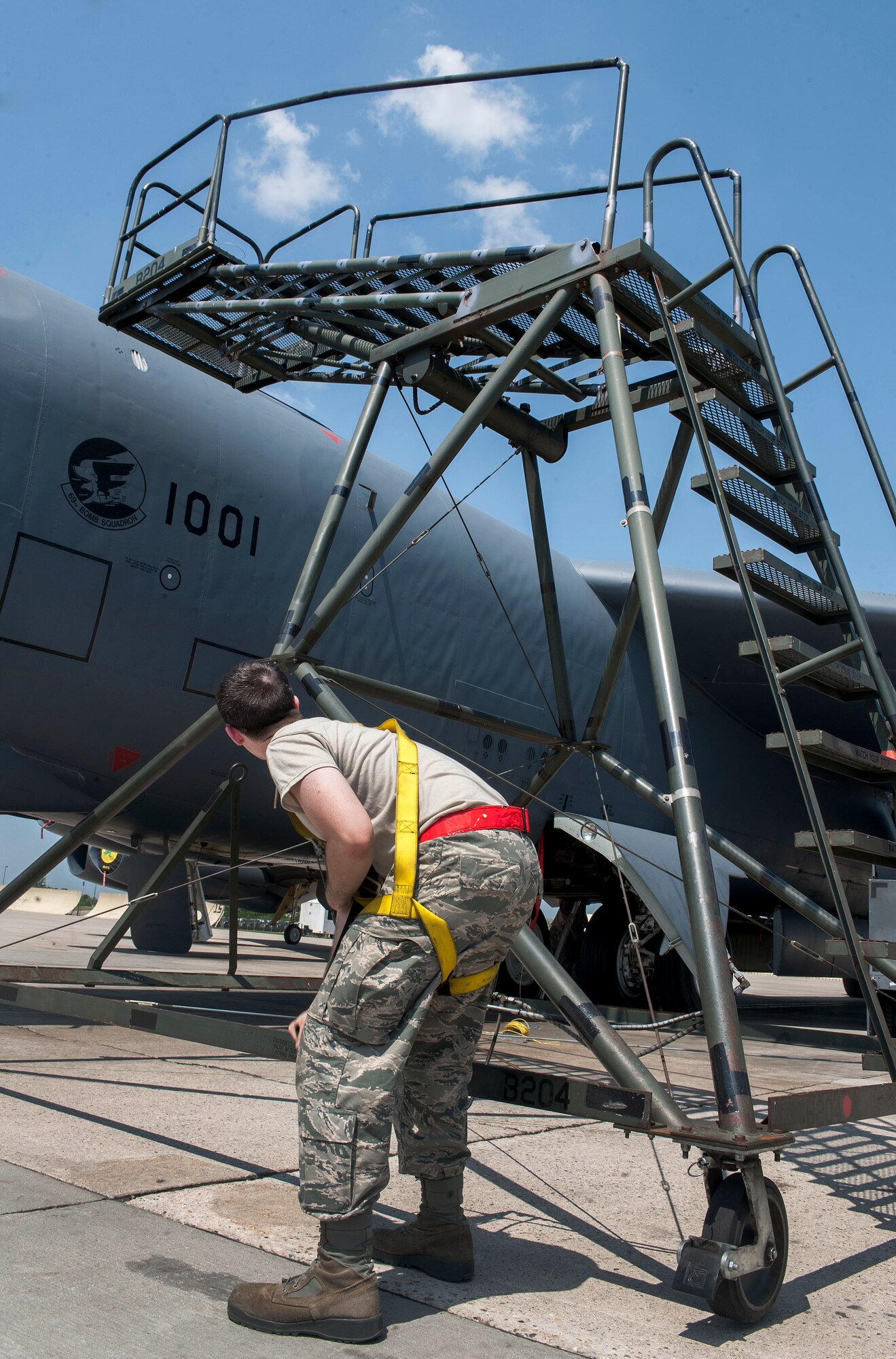 Airman Michael Henderson, 5th Aircraft Maintenance Squadron crew chief, checks the position of a B-204 maintenance stand in relation to a B-52H Stratofortress at Minot Air Force Base, N.D., June 11, 2015. The stand allows maintenance Airmen to safely work on hard-to-reach places, such as the in-flight refueling door, at the top of the Aircraft. (U.S. Air Force photo/Senior Airman Stephanie Morris)