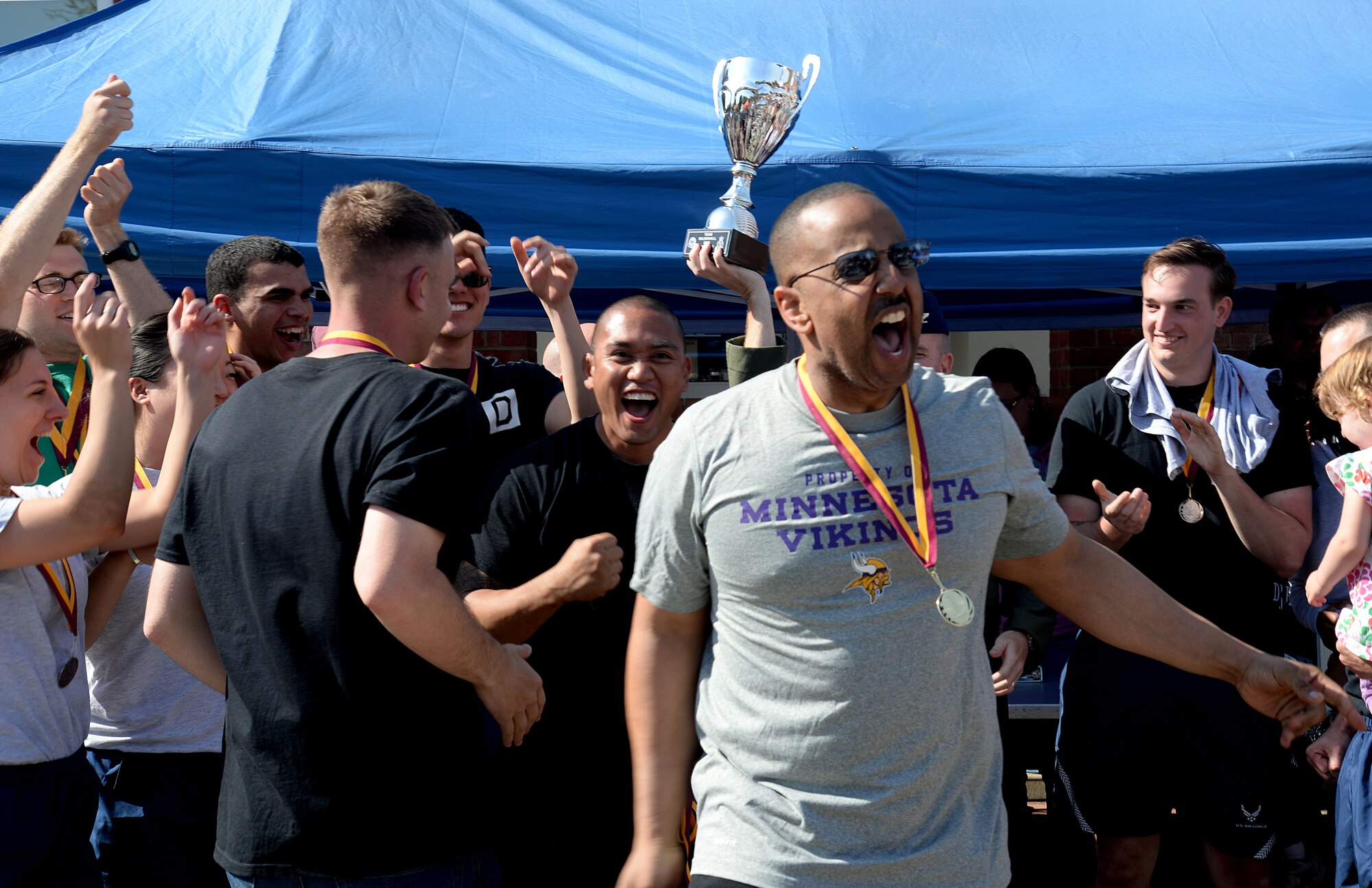 U.S. Air Force Airmen from of the 100th Air Refueling Wing staff agencies celebrate winning the Marauder Melee sports competition June 11, 2015, on RAF Mildenhall, England. After a 5k run, the event  consisted of several fitness challenges including volleyball, soccer and rock climbing, of which Wing Staff Agency teams either won first or second place earning them the most overall points amongst several groups and squadrons. (U.S. Air Force photo by Senior Airman Kate Thornton/Released)