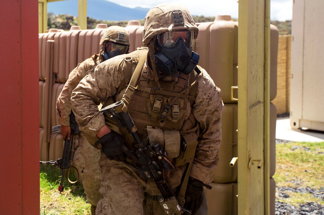 Marines wearing their protective gas masks advance toward their next objective during Operation Lava Viper at Pohakuloa Training Area, Hawaii, June 10, 2015.