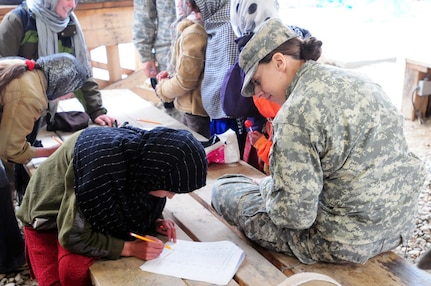 Army Capt. Nicole Zupka, a battlewatch captain with Combined Joint Task
Force-Paladin, helps an Afghan child with her writing skills during Female
Engagement Team training on Bagram Air Field, Feb. 3. Four Wisconsin
National Guard Soldiers have recently been selected for this program. Female
Engagement Team training teaches Dari and Pashto language, Afghan culture,
Afghan religion and many other lessons to prepare for future engagements.