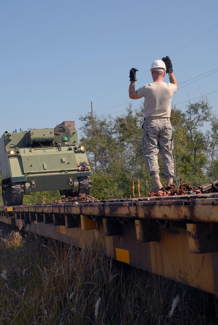 A Solider from the Florida Army National Guard's 3rd Battalion, 116th Field Artillery Regiment, guides a M577 armored personnel carrier onto a railroad car March 22, 2011, in preparation for an upcoming annual training period at Fort Stewart, Ga.