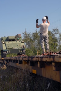 A Solider from the Florida Army National Guard's 3rd Battalion, 116th Field Artillery Regiment, guides a M577 armored personnel carrier onto a railroad car March 22, 2011, in preparation for an upcoming annual training period at Fort Stewart, Ga.