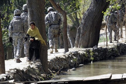 Members of the Iowa National Guard’s 734th Agribusiness Development Team pass an Afghan girl as they conduct a foot patrol down the Asadabad canal to determine if the canal needs to be cleaned March 22, 2011.