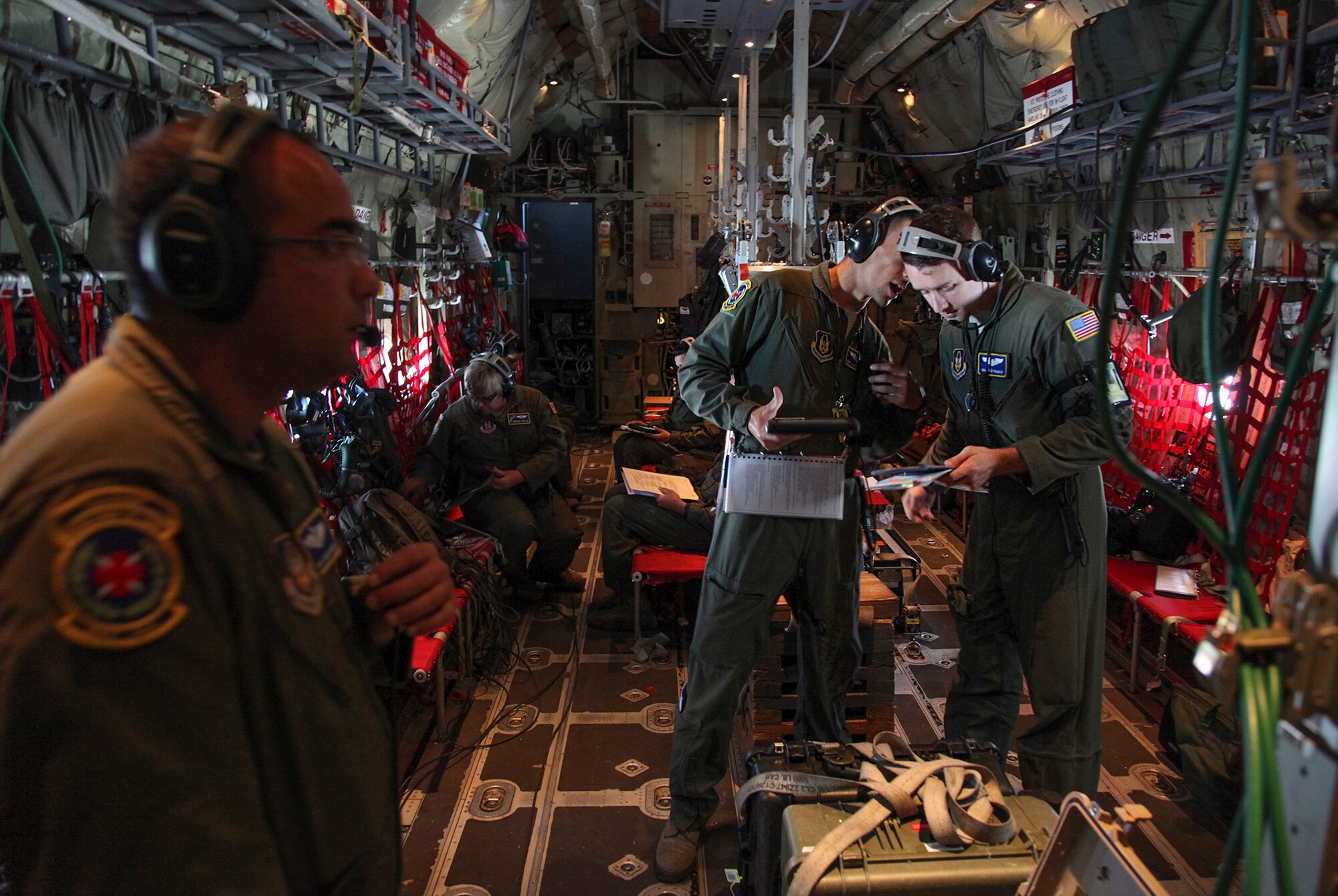 TRAVIS AIR FORCE BASE, Calif. -- Members of the 349th Aeromedical Evacuation Squadron discuss procedures during flight above Northern California aboard a C-130J Super Hercules June 6, 2015.  The 349th Aeromedical Evacuation Squadron transformed the four-engine tactical transport into a flying hospital. In turn, the CCATT teams from the 60th Surgical Operations Squadron and the 349th Aeromedical Staging Squadron established onboard what was essentially a portable intensive care unit dedicated to one very ill, simulated, "patient." The C-130J was from the California Air National Guard's 146th Airlift Wing. (U.S. Air Force photo/Lt. Col. Robert Couse- Baker/Released)