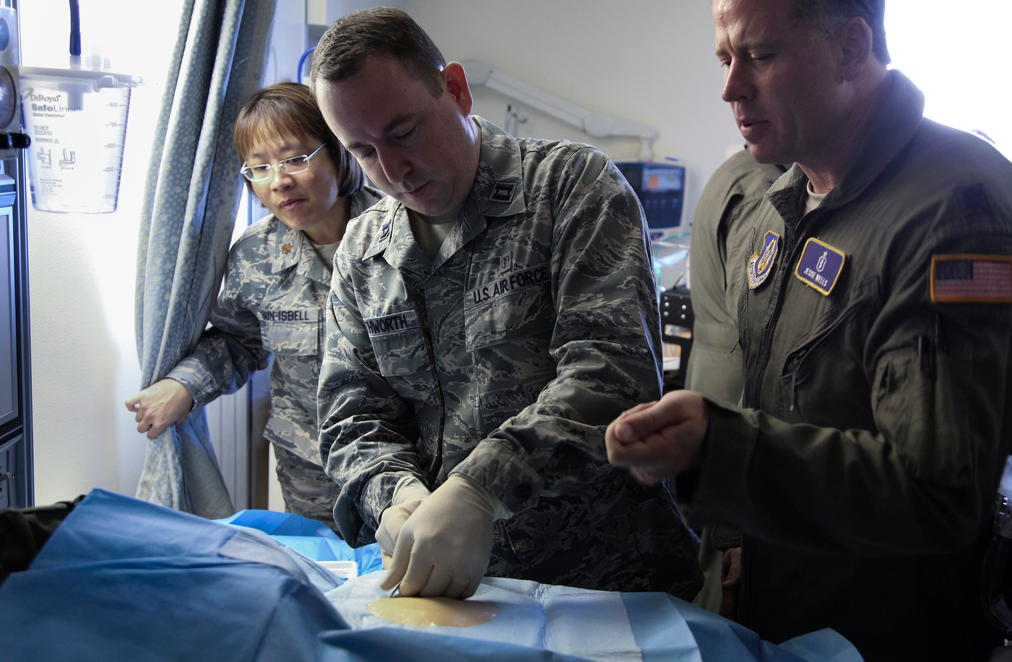 TRAVIS AIR FORCE BASE, Calif. -- Capt. Ryan Southworth, a critical care nurse with the 349th Aeromedical Staging Squadron, inserts a central line IV into the chest of a simulated patient as Maj. Theresa Sun-Isbell, a critical care nurse with the 349th ASTS, and Lt. Col. (Dr.) Jesse Wells, 349th Medical Squadron, look on. The Reserve medical personnel were preparing to practice transporting a critically ill patient as part of a critical care air transport team during 349th Air Mobility Wing Air Force Specialty Code training June 6, 2015, at David Grant USAF Medcial Center, Travis Air Force Base, California.  In preparation for the training, the 349th Aeromedical Evacuation Squadron transformed the four-engine tactical transport into a flying hospital. In turn, the CCATT teams from the 60th Surgical Operations Squadron and the 349th Aeromedical Staging Squadron established onboard what was essentially a portable intensive care unit dedicated to one very ill, simulated, "patient."  (U.S. Air Force photo/Lt. Col. Robert Couse- Baker/Released)
