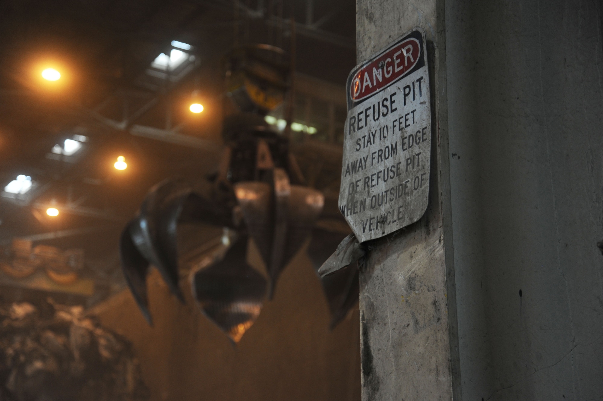 The trash collection claw looms behind a warning sign at the Waste to Energy plant in Spokane, Wash., June 16, 2015. The claw helps to deposit trash for burning in two boilers. (U.S. Air Force photo/Senior Airman Sam Fogleman)