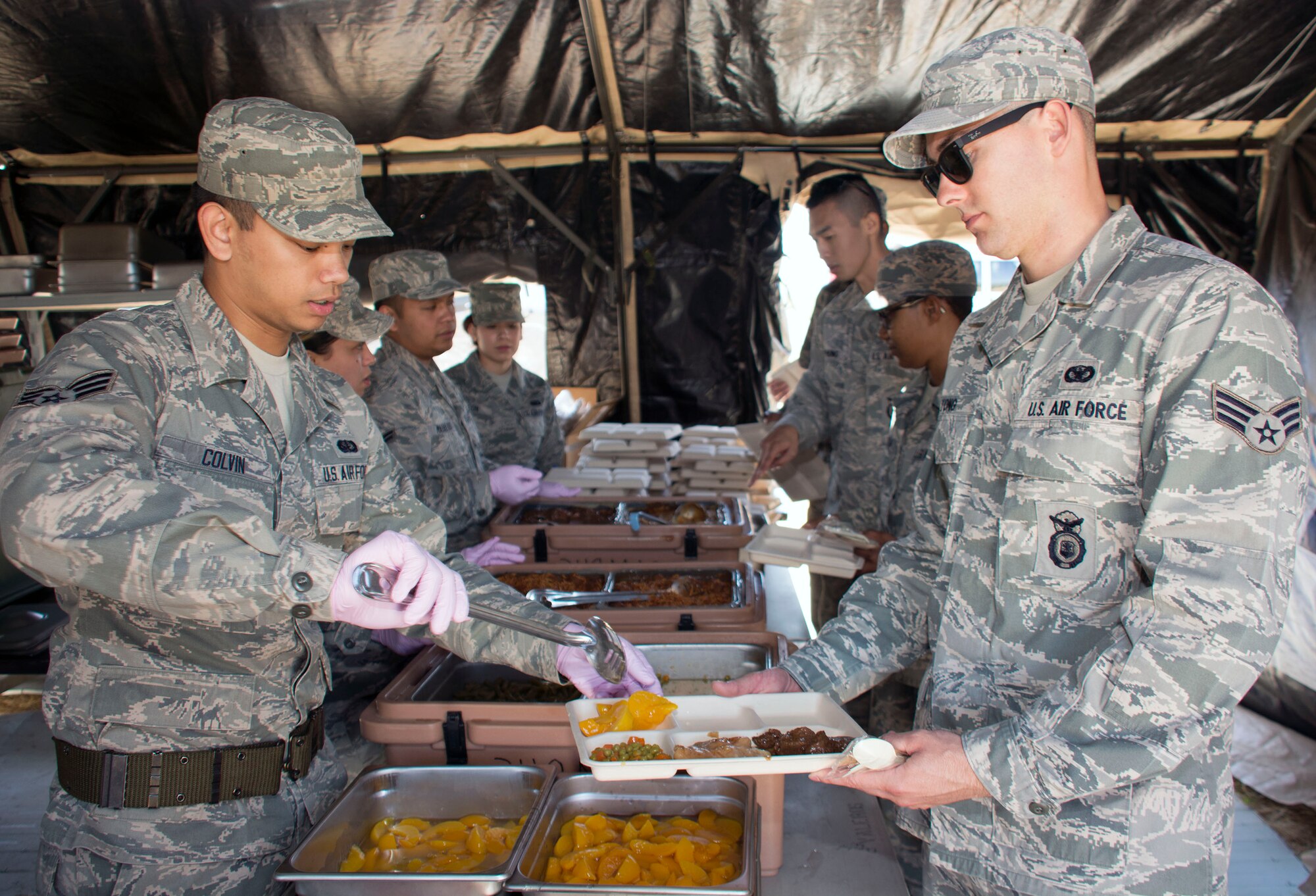 TRAVIS AIR FORCE BASE, Calif. -- Airman 1st Class Andrew Colvin, 349th Force Support Squadron, serves peaches to Senior Airman Eric Tong, 349th Security Forces Squadron June 6, 2015 in the single palletized expeditionary kitchen at Travis Air Force Base, California. The SPEK can serve approximately 550 personnel when utilized in the field. (U.S. Air Force photo/Staff Sgt. Christopher Carranza)