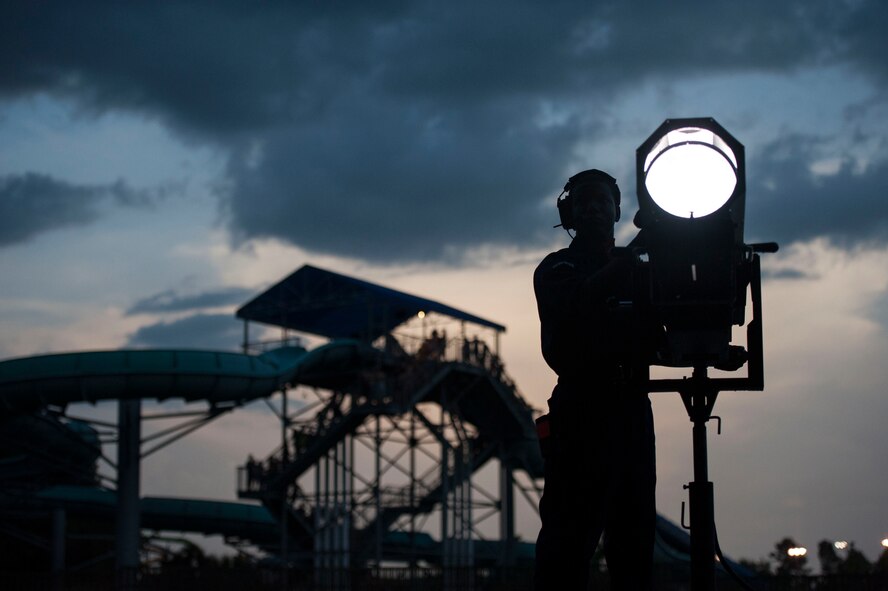 U.S. Air Force Staff Sgt. Ronald Brooks, Tops in Blue transportation NCO in charge, works the spotlight during a performance June 12, 2015, at Wild Adventures in Valdosta, Ga. In addition to technical personnel, the performers are also responsible for transporting, loading, unloading and setting up over 65,000 pounds of equipment required for each show.  (U.S. Air Force photo by Andrea Jenkins/Released) 

